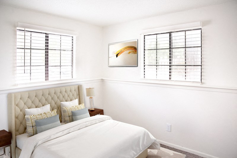 a white bedroom with a bed and two windows