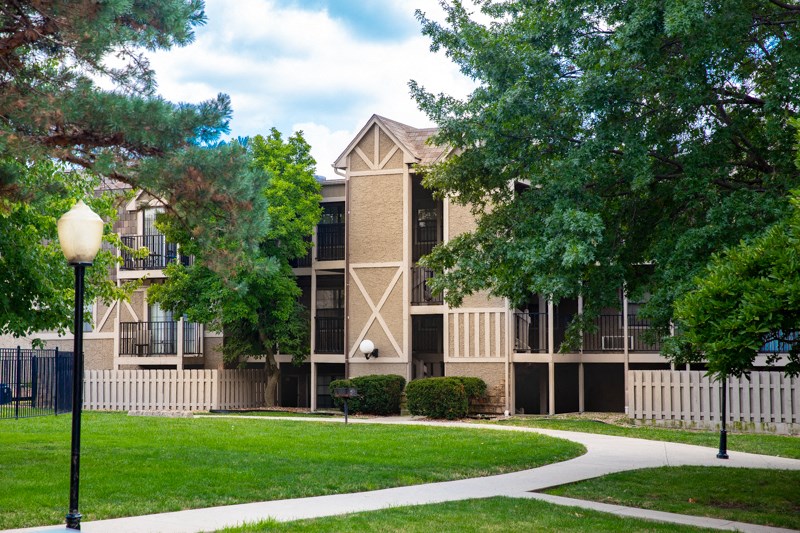 an apartment building with a green lawn and trees