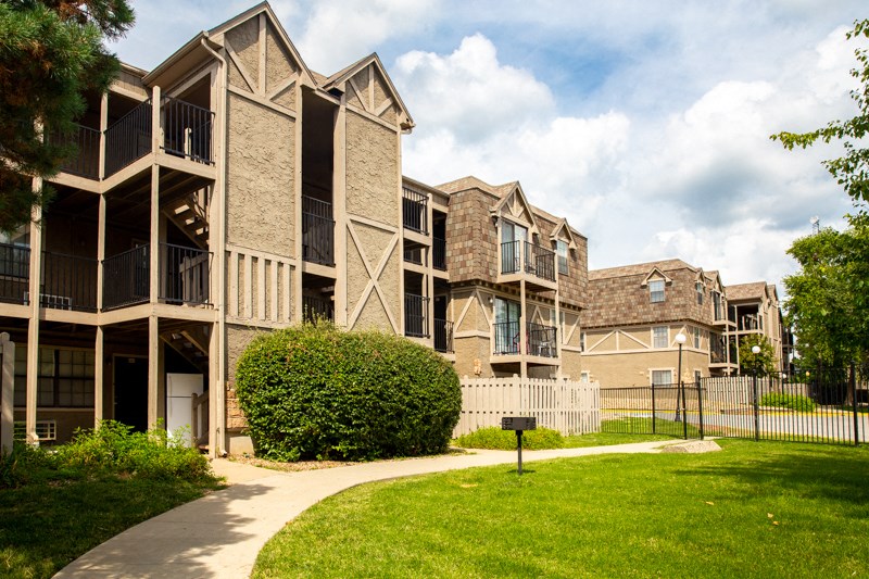 an apartment building with a sidewalk in front of it