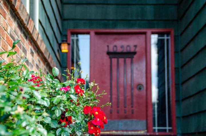 a red door on a house with red flowers in front of it