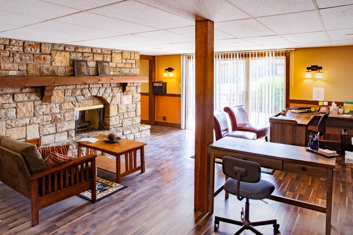 a living room with a stone fireplace and a desk