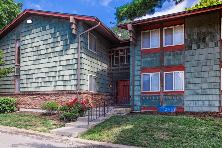 the front of a green and red house with a red door
