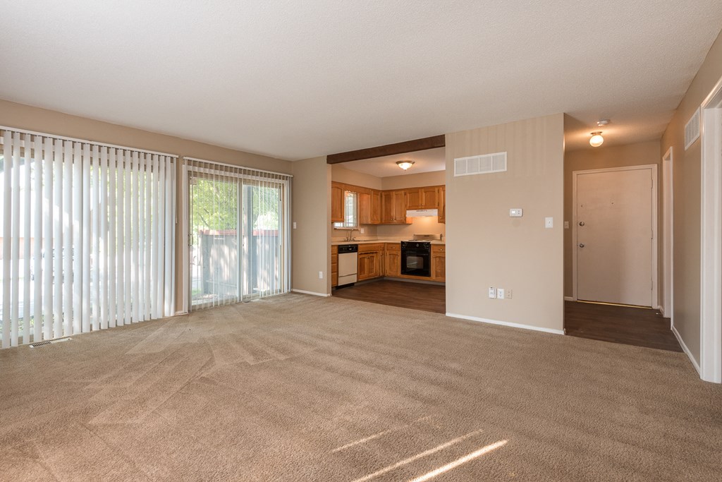 an empty living room with sliding glass doors to a kitchen