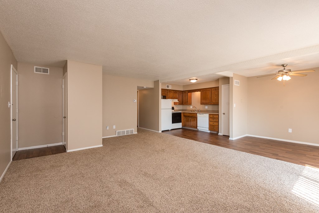 an empty living room and kitchen with a ceiling fan