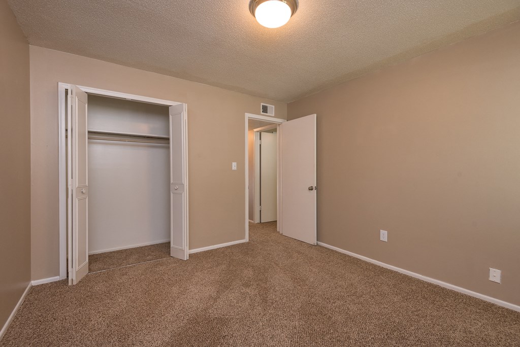 an empty living room with a closet and a door to a hallway