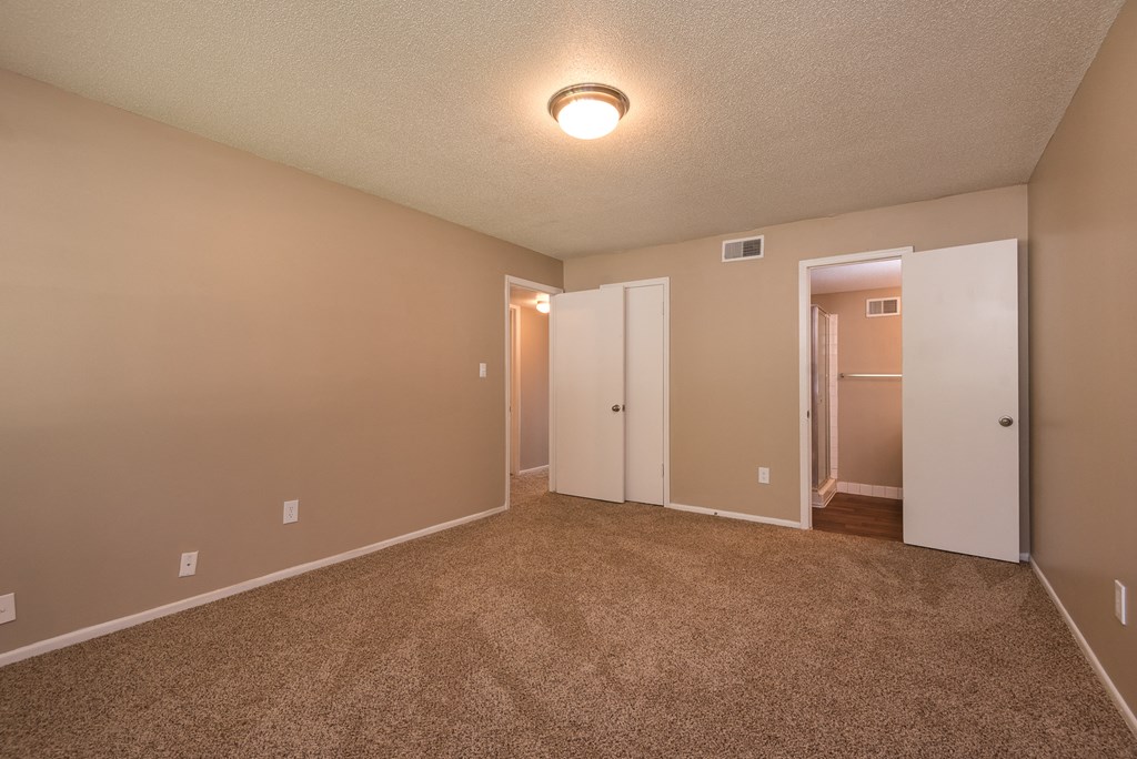 an empty living room with carpet and a door to a closet