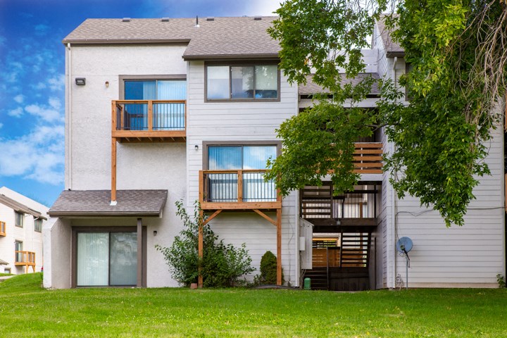 a white apartment building with a yard and a tree