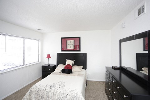 a bedroom with a bed and a dresser and a window