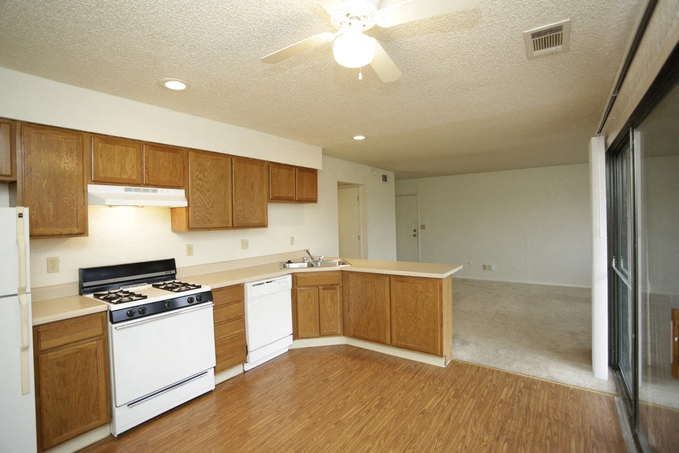 an empty kitchen with white appliances and wooden cabinets