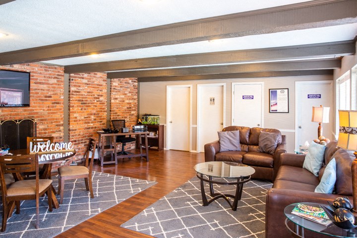 a living room with leather furniture and a brick wall