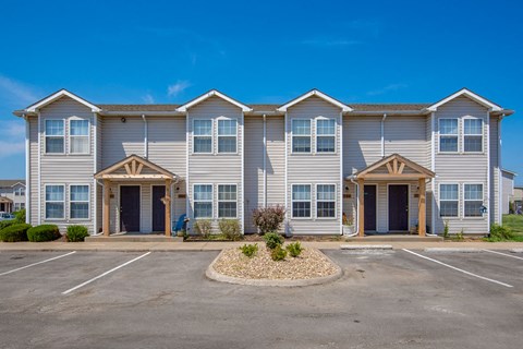 the exterior of a building with two entrances and a parking lot