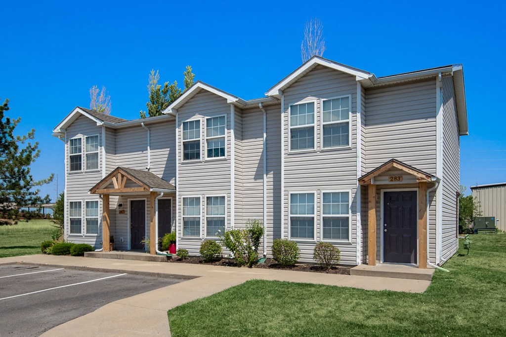a gray house with brown trim and a driveway