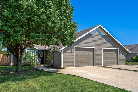the front of a house with a garage door and a tree