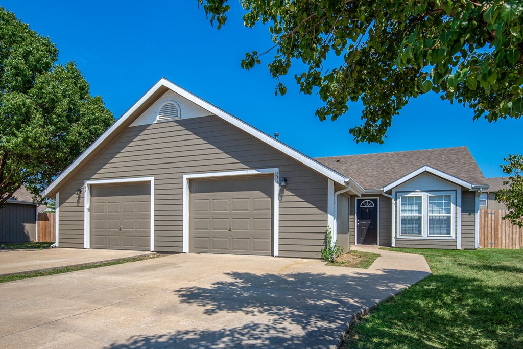 the front of a house with a driveway and two garage doors