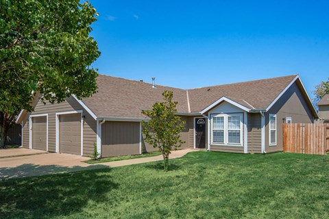 the front of a house with a lawn and a tree