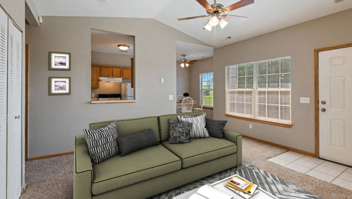 a living room with a green couch and a ceiling fan