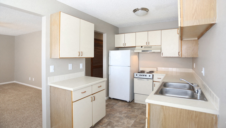 an empty kitchen with white appliances and white cabinets