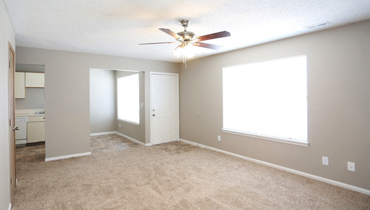 an empty living room with a ceiling fan and a window