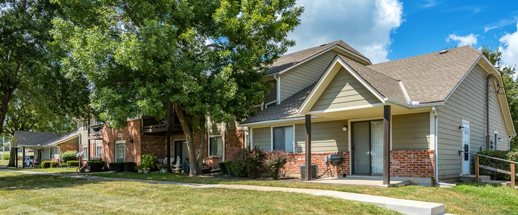 a house with a porch and a tree in front of it