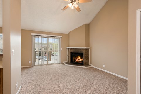 an empty living room with a fireplace and a ceiling fan