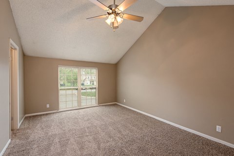 an empty living room with a ceiling fan