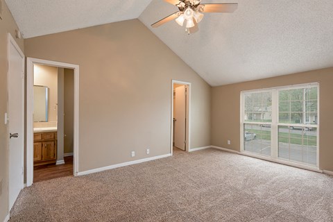 an empty living room with a large window and a ceiling fan