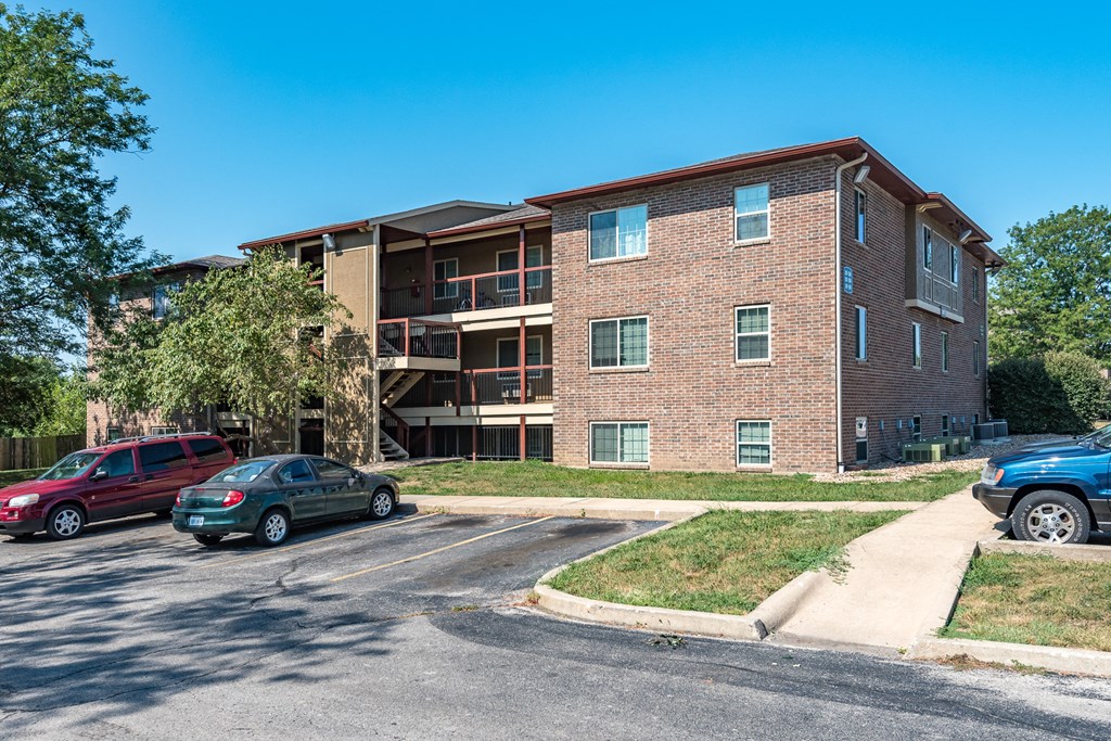 a brick apartment building with cars parked outside