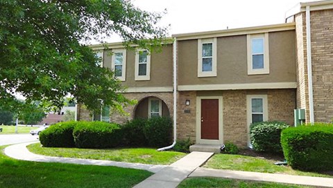 a brick building with a red door and a sidewalk