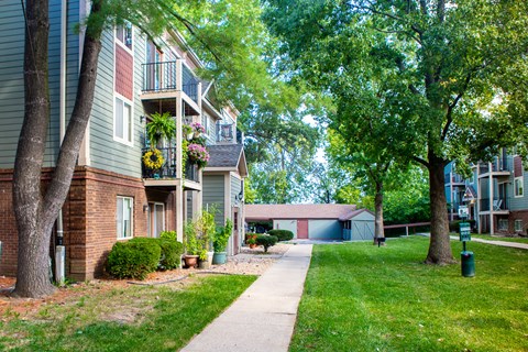 a sidewalk in front of an apartment building with trees