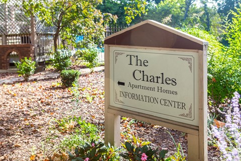 a sign for the charles apartment homes information center in a garden