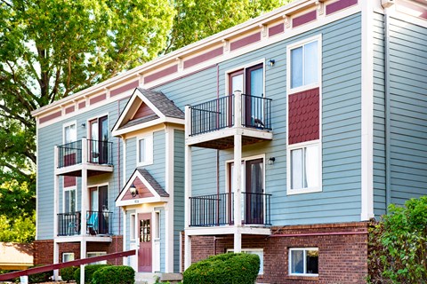 a row of blue apartments with balconies and trees