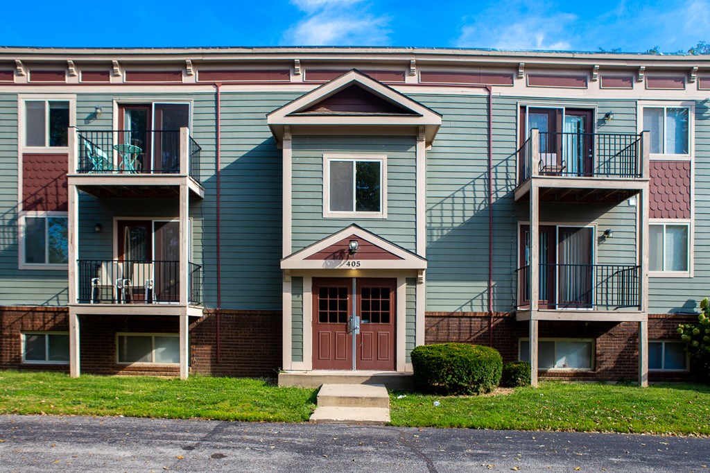an apartment building with two balconies and a red door