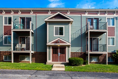 an apartment building with two balconies and a red door