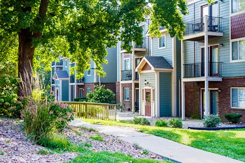 a row of apartment buildings with trees and a sidewalk