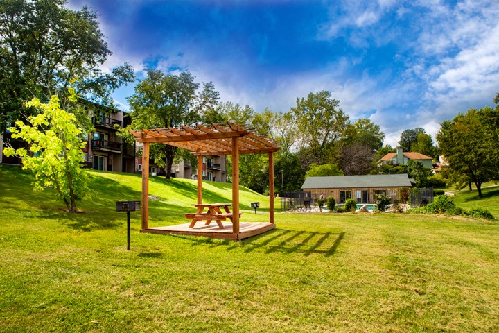 a wooden swing in a park with a house in the background