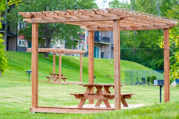 a picnic table under a wooden structure in a park