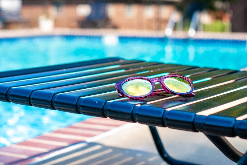 a pair of sunglasses sitting on a bench near a swimming pool