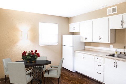 a kitchen with white cabinets and a table with chairs