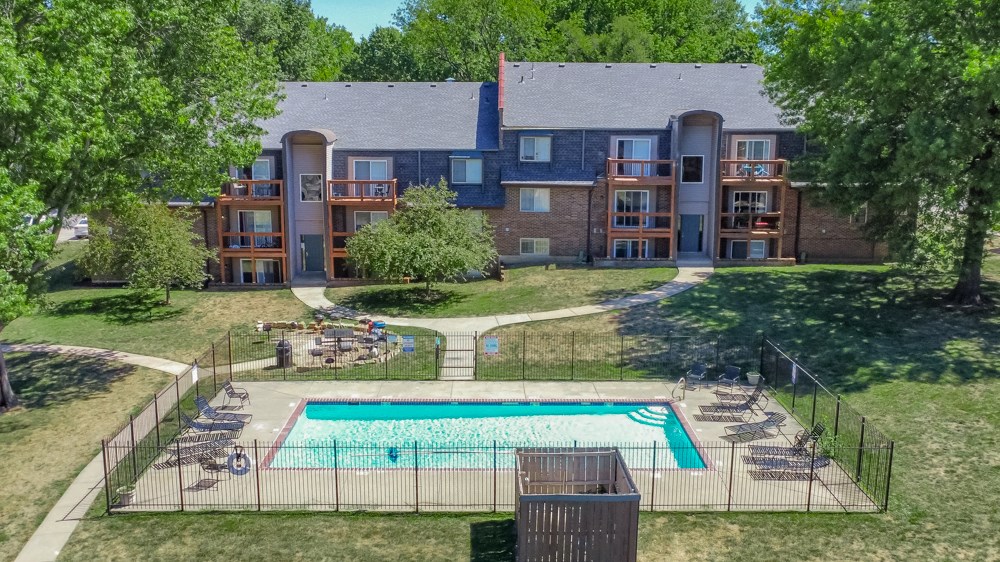 an aerial view of a pool with an apartment building in the background