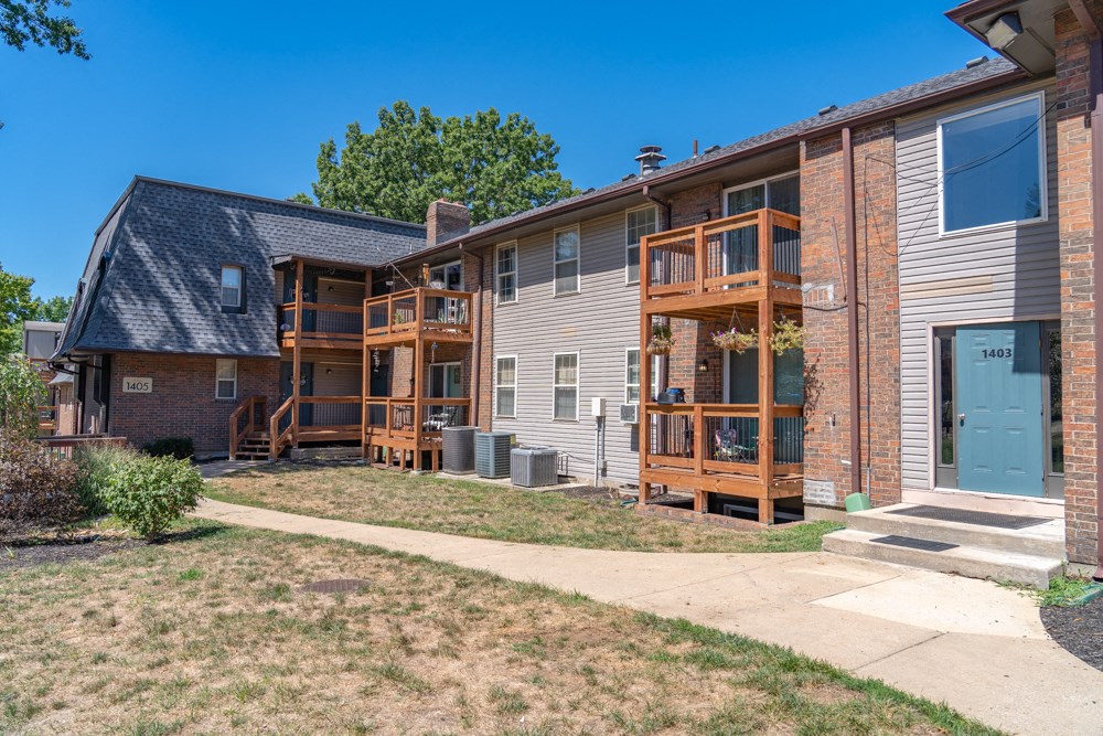 a brick apartment building with wooden balconies and a sidewalk