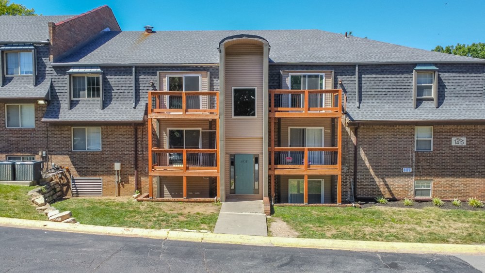 a brick apartment building with wooden balconies and a gray roof