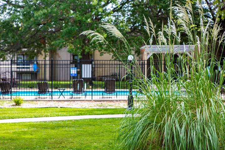 a pool with a fence and chairs in a yard