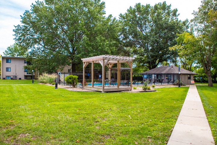 a gazebo in the middle of a yard with a swimming pool