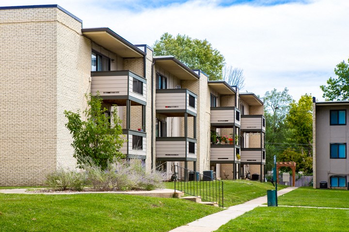 a row of apartment buildings with grass and trees