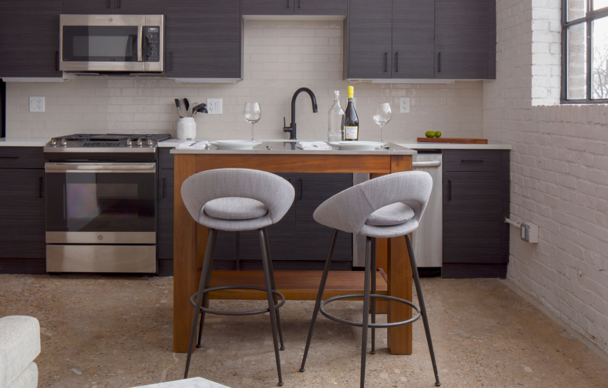 a kitchen with two stools in front of a kitchen counter