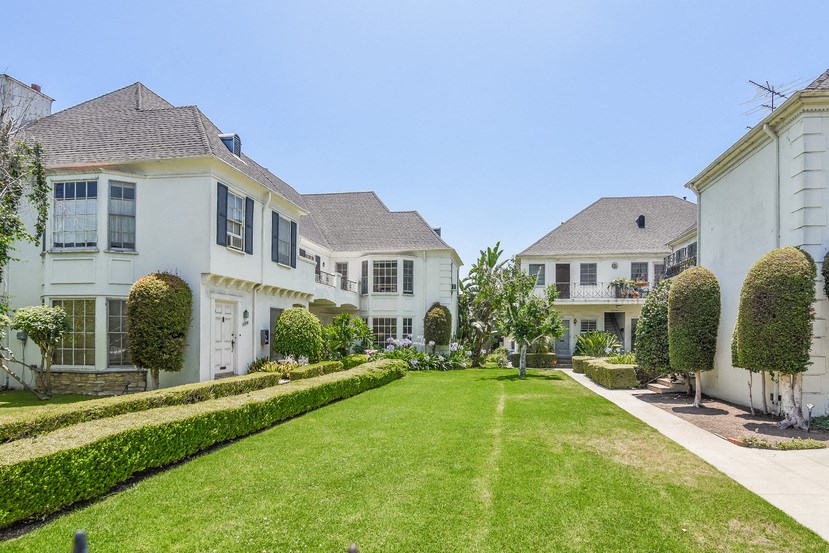 a row of white houses with a lawn and a garden