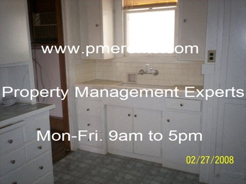 a kitchen with white cabinets and a sink and a window