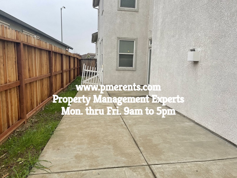 a sidewalk in front of a house with a wooden fence