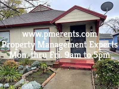 A house with a sign that says www.pmerents.com Property Management Experts Mon. thru Fri. 9am to 5pm.