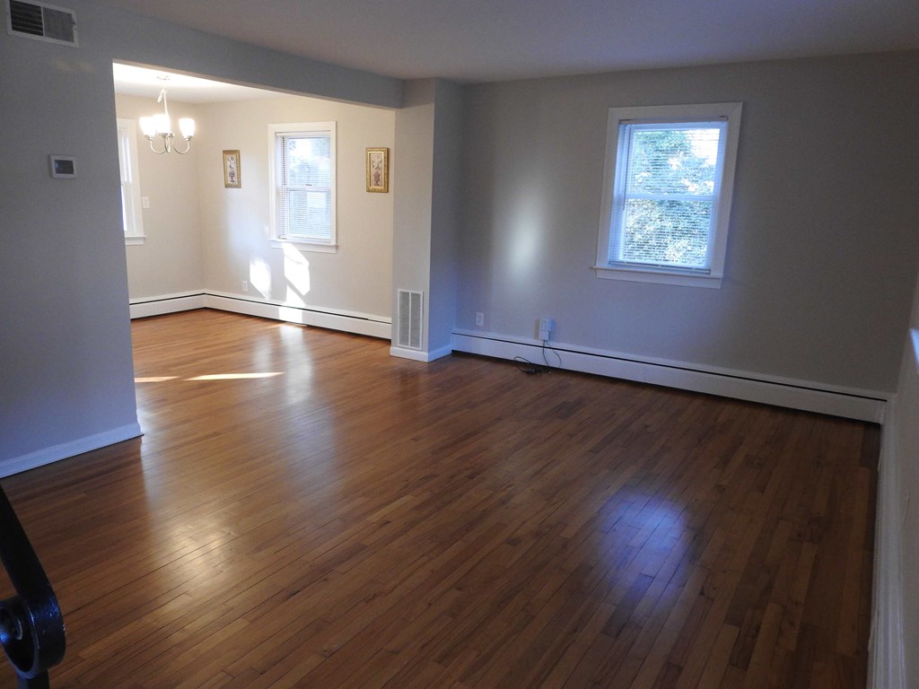 an empty living room with wooden floors and a window
